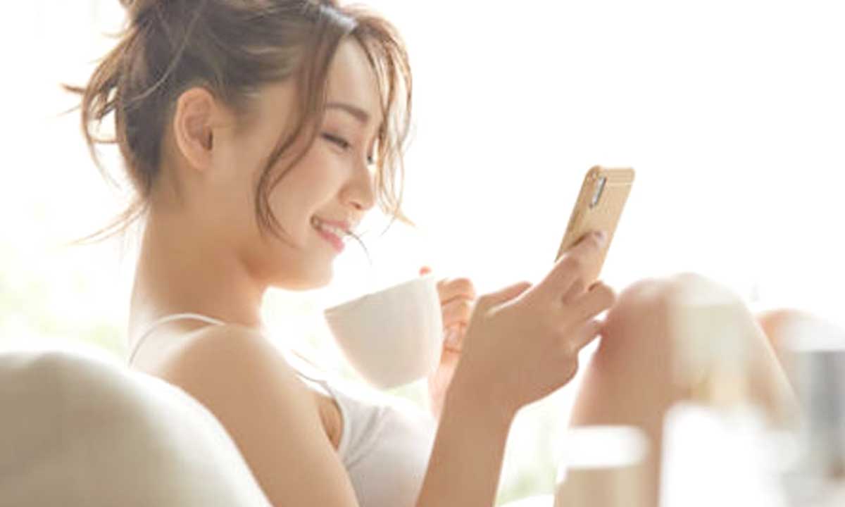 白い部屋でスマホを操作する女性