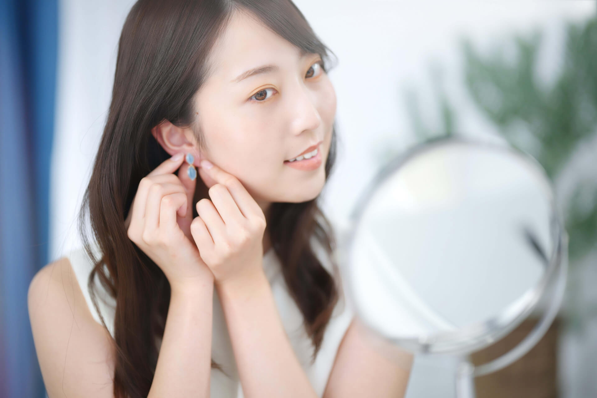 鏡の前でピアスをつける女性
