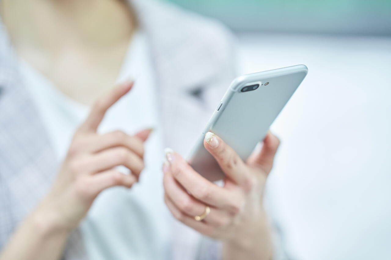 白いジャケットを着た女性のスマホ操作